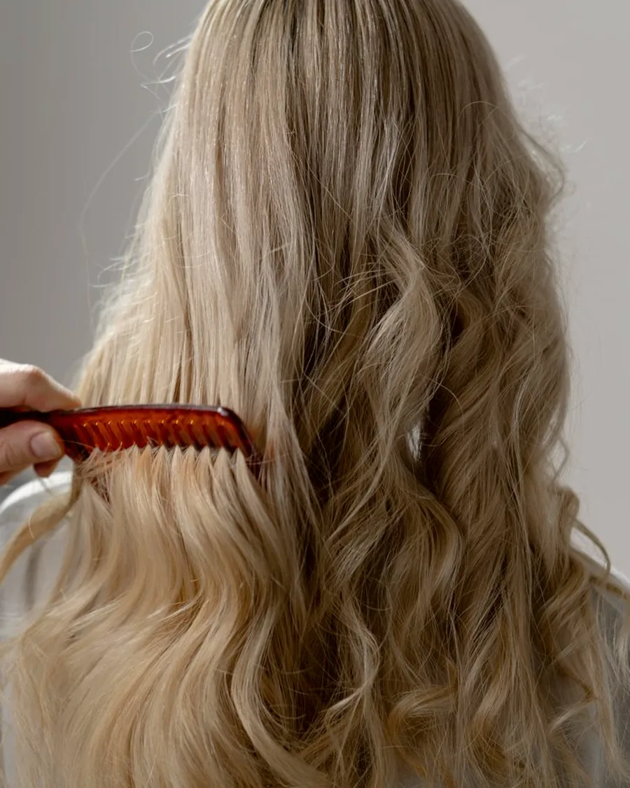 Longs cheveux blonds ondulés peignés après un brushing